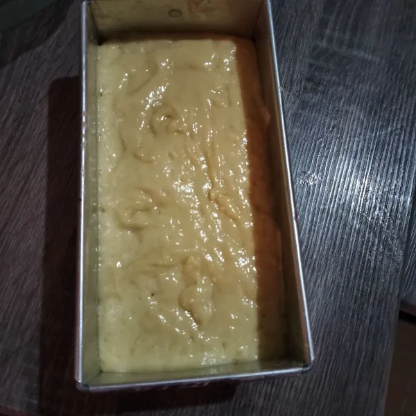 Olesi cetakan dengan margarin, beri kertas roti di bagian bawahnya. Tuang adonan, lalu ratakan.