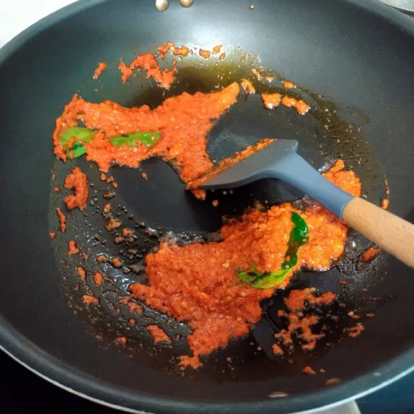 Blender cabe merah keriting dan bawang putih menggunakan sedikit minyak goreng lalu tumis bersama daun jeruk hingga mengeluarkan minyak.