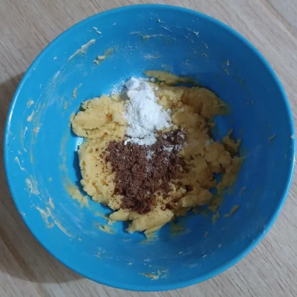 Masukkan tepung terigu, aduk rata. Lalu tambahkan coklat bubuk dan baking powder serta vanili.