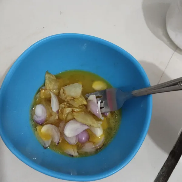 Masukkan kentang dan bawang merah ke dalam telur dan aduk rata.