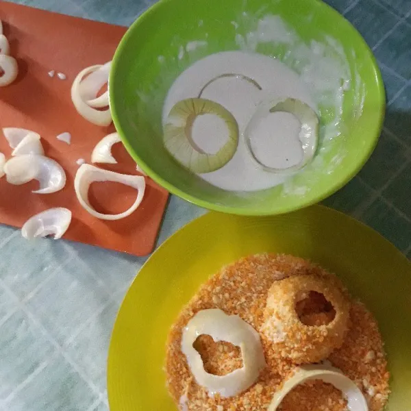 Celupkan lapisan bawang bombay ke dalam adonan tepung terigu, lalu balur dengan tepung roti. Lalu ulangi agar tepungnya tebal.