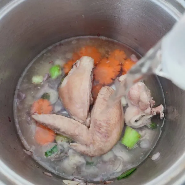 Masukkan potongan wortel, ayam rebus dan sisa air. Rebus dengan api kecil hingga ayam dan wortel empuk.