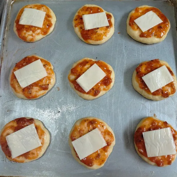 Olesi permukaan adonan dengan saus bolognese kemudian letakkan keju slice.
