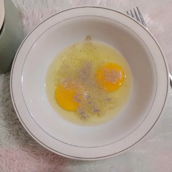 Pecahkan telur di dalam wadah, beri garam, lada bubuk dan kaldu jamur lalu kocok rata.
