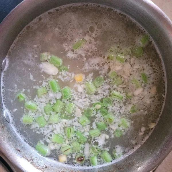Masukkan sayuran dan potongan daging ayam ke dalam sop.