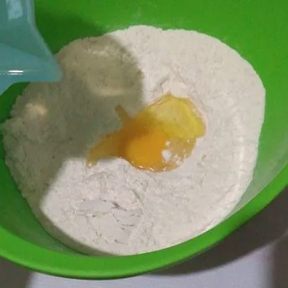 Masukkan telur kemudian tuang air, uleni hingga rata.