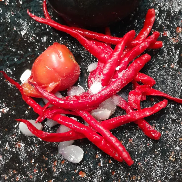 Masukkan ke dalam batu giling bahan sambal tomat lalu beri garam.