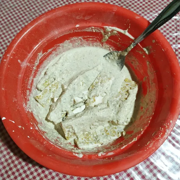 Masukkan tempe ke dalam adonan tepung, aduk merata.