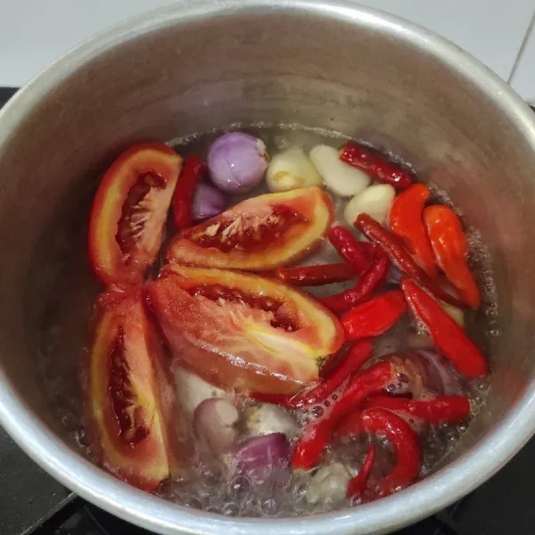 Rebus tomat, cabai merah, cabai rawit, bawang merah, dan bawang putih. Masak sampai layu, tiriskan.