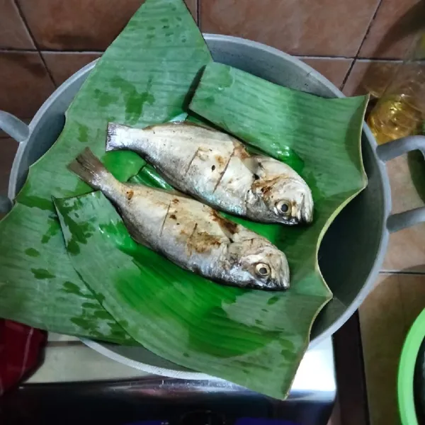 Panaskan wajan, kemudian tata daun pisang di atasnya,lalu masukkan ikan yg sudah di marinasi tadi.