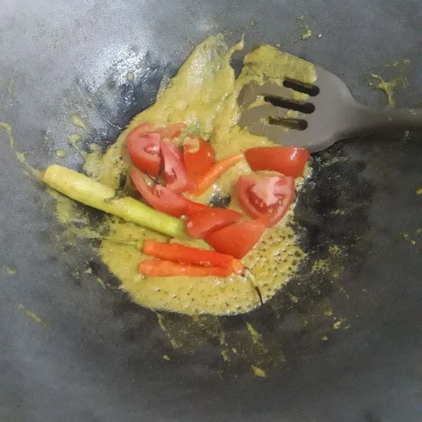 Panaskan minyak goreng dalam wajan lalu masukkan bumbu halus bersama serai dan daun salam. Tumis sampai harum lalu masukkan tomat dan cabe rawit, aduk merata.