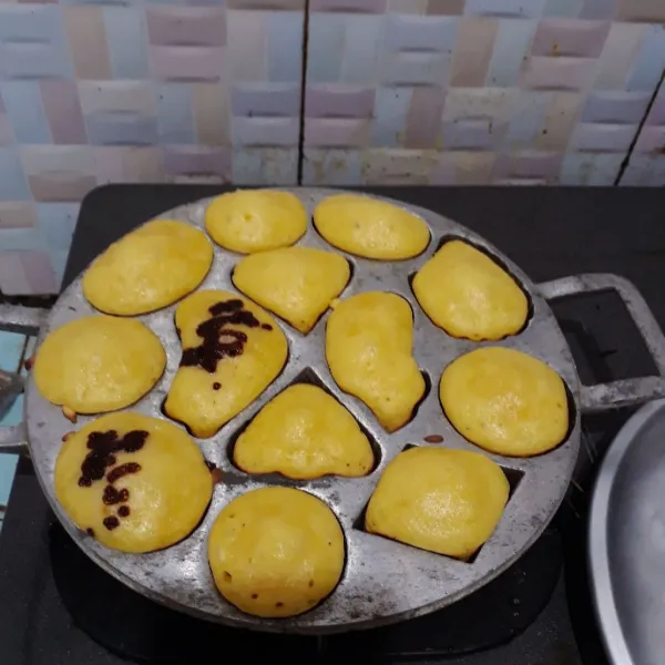 Panaskan cetakan dengan api kecil dan olesi tipis margarin. Tuang adonan ke dalam cetakan dan taburi toping. Tutup cetakan dan masak hingga kue matang.