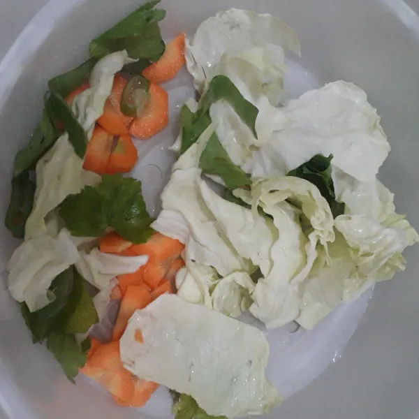 Potong-potong kubis, daun bawang dan seledri. Kupas dan potong-potong wortel. Cuci bersih semua sayuran.