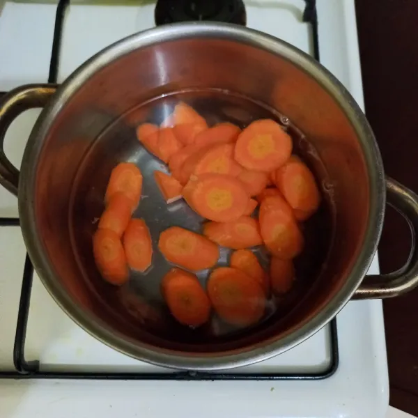 Didihkan air pada panci, masukkan irisan wortel.