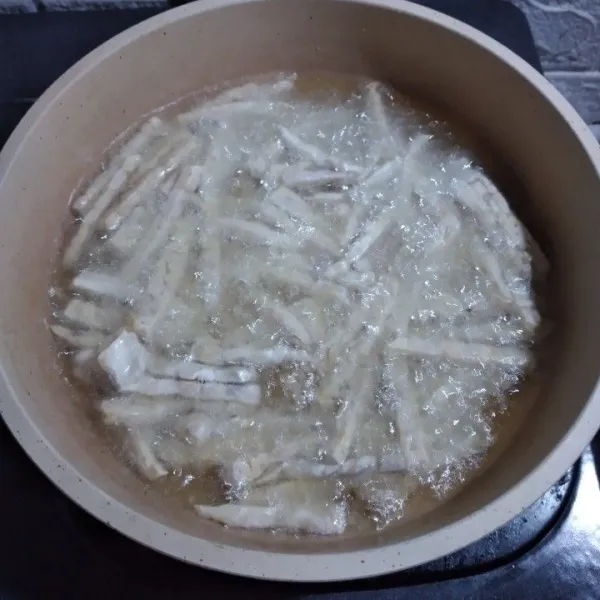 Potong tempe bentuk kecil memanjang, goreng dalam minyak banyak yang panas.