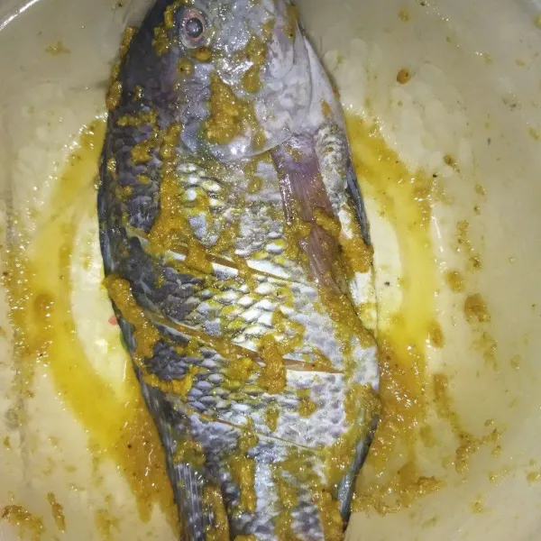 Haluskan bawang putih, ketumbar, jahe dan kunyit, lalu lumuri ikan dengan bumbu halus, beri garam, ratakan, biarkan ikan sekitar 15 menit.