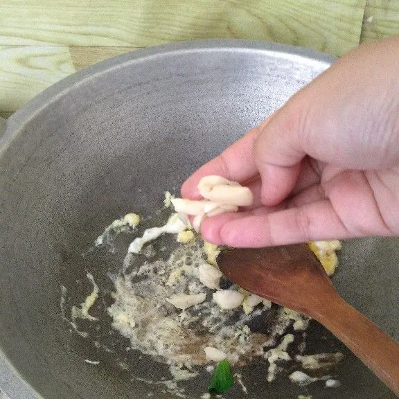 Orak-arik telur kemudian pinggirkan ditepi wajan. Masukkan bawang putih geprek dan tumis sampai aromanya harum.