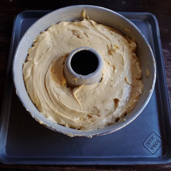 Olesi loyang tulban diameter 22 cm dengan margarin dan taburi tipis terigu. Tuang adonan ke dalam loyang dan ratakan.