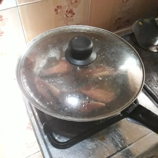 Goreng ikan tongkol sambil ditutup hingga matang dan kecoklatan.