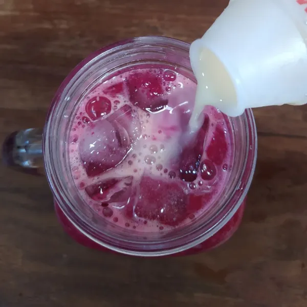 Tuang ke dalam gelas saji berisi es batu. Tuang minuman probiotik. Sajikan.