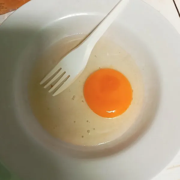 Pecahkan 1 butir telur berukuran sedang ke piring.