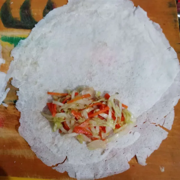 Ambil kulit lumpia, beri isian tumisan sayur. Oles bahan perekat. Lipat seperti amplop.