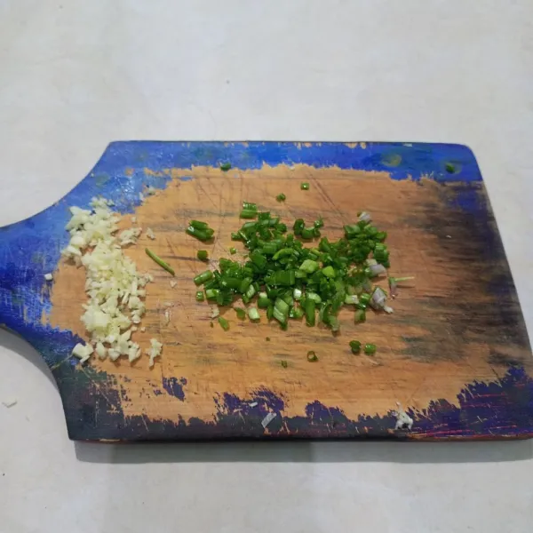 Cincang halus bawang putih dan potong-potong kecil daun bawang.