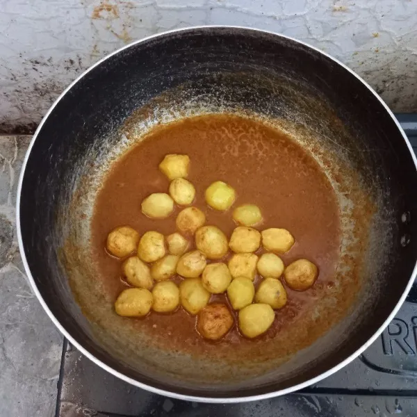 Masukkan kentang mini sambil diaduk-aduk hingga tercampur merata dengan bumbu.