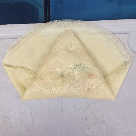 Lipat bagian kanan dan kiri, lalu lipat ke depan. Rekatkan bagian kanan dan kiri ke tengah.