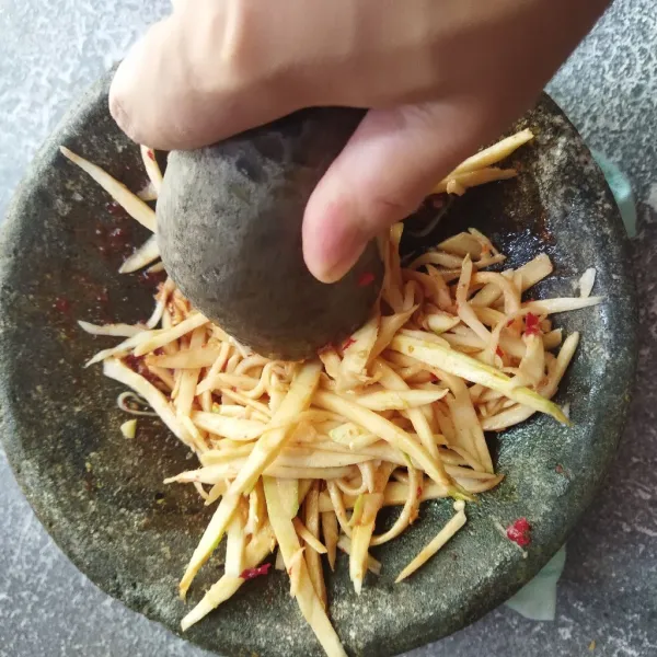 Campur mangga dengan sambal sambil diuleg perlahan agar rasa asamnya keluar.