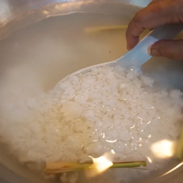 Masukkan nasi putih ke dalam wajan yang berisi air mendidih dan serai.