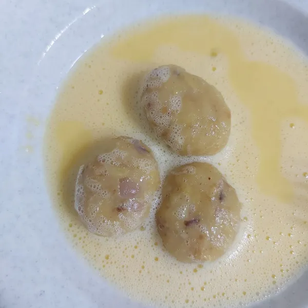 Kocok telur ayam agak lama hingga tekstur agak cair dan berbuih. Masukkan perkedel hingga semua sisinya terbalur dengan rata.