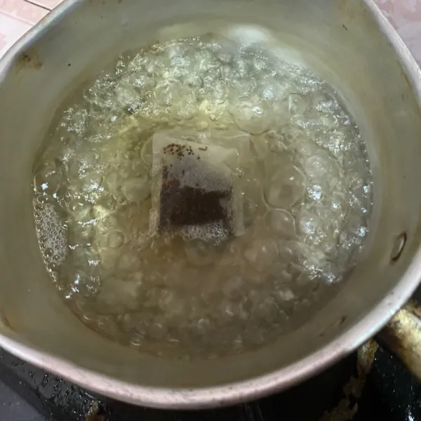 Rebus air mendidih lalu masukkan satu buah teh kemasan masak hingga warna tehnya keluar dan airnya panas.
