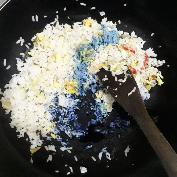 Masukkan nasi.Tambahkan air bunga telang.Tambahkan garam, kaldu jamur, lada bubuk.Aduk sampai tercampur rata dan nasi goreng telah matang.