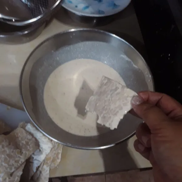 Celupkan tempe satu persatu ke dalam adonan tepung.
