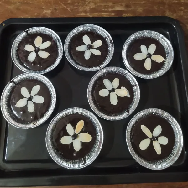 Tuang ke cup aluminium foil atau ke cetakan muffin yang sudah dialasi paper cup. Isi setinggi ¾ saja.
Beri choco chip dan almond slice.