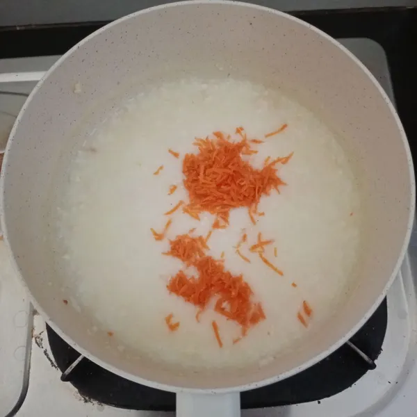 Setelah tekstur nasi berubah menjadi bubur, masukkan tempe dan wortel. Masak kembali sekitar 7-10 menit.
