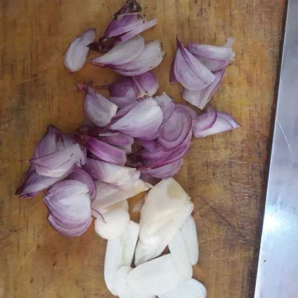 Kupas dan iris bawang merah dan bawang putih.