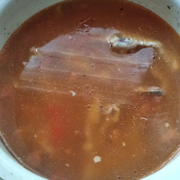 Masukkan tumisan tomat dan bawang ke dalam rebusan tulang ayam.