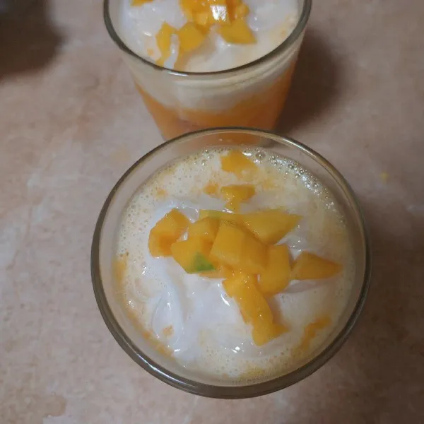 Tambahkan jeli kelapa, krimer kental manis, dan susu evaporasi. Beri toping irisan buah mangga.