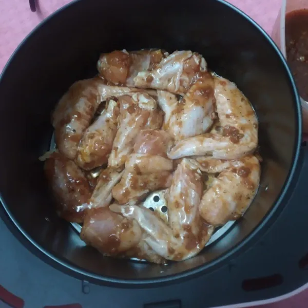 Masukkan sayap ayam ke dalam air fryer, masak suhu 200°C selama 30 menit. Setelah 15 menit, olesi dengan bumbu marinasi, masak kembali hingga matang.