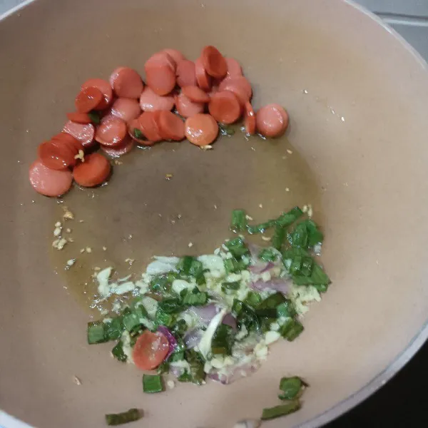 Goreng irisan sosis dengan sedikit minyak. Masukkan daun bawang dan bumbu halus. Tumis hingga harum.
