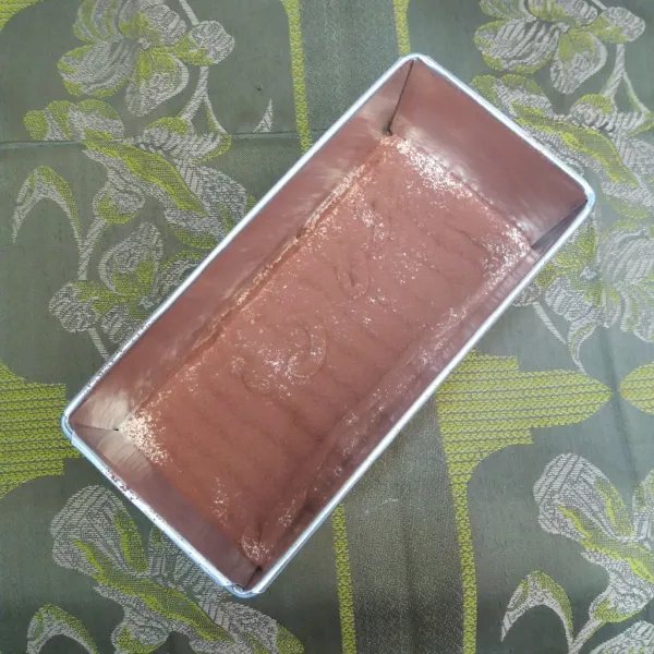 Bagi adonan menjadi 2 bagian, beri pewarna makanan ke salah satu bagian, aduk rata, tuang sebagian adonan original ke loyang, dan taburi cokelat bubuk.