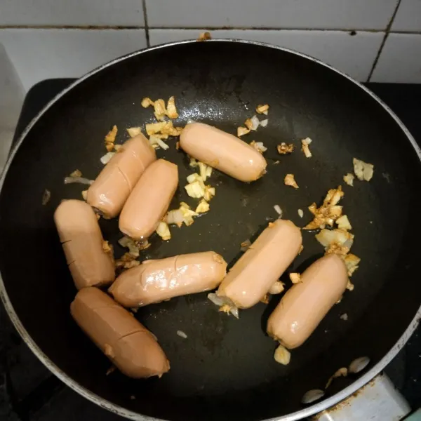 Setelah bawang harum dan berubah warna, masukkan sosis lalu aduk rata.