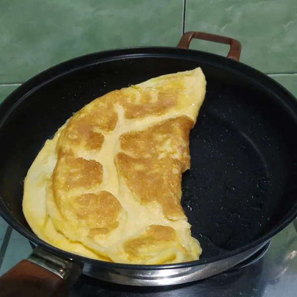 Panaskan minyak di atas teflon, lalu dadar telur hingga matang. Lipat telur membentuk setengah lingkaran.