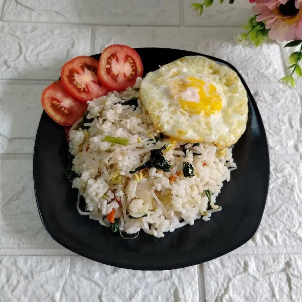 Tuang nasi goreng ke piring. Sajikan dengan telur ceplok dan irisan tomat.