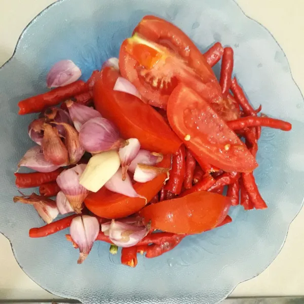 Siapkan bahan sambel. Cuci, potong-potong cabe dan tomat. Kupas dan iris duo bawang.