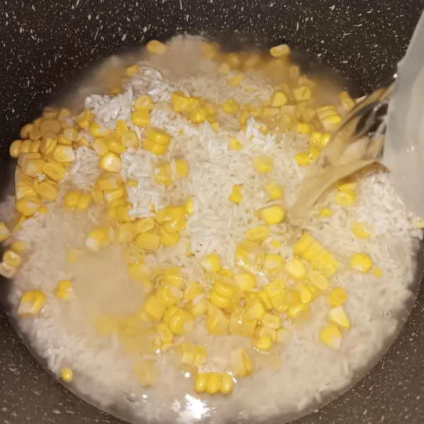 Masukkan beras kedalam panci bersama jagung sisir dan 1200 ml kaldu tulang ayam. Masak dengan api kecil.