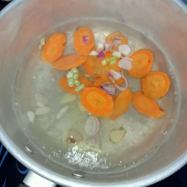 Rebus air hingga mendidih, masukkan bawang merah, bawang putih, kemudian masukkan wortel. Masak hingga wortel setengah matang.