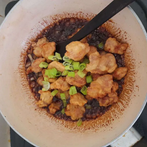 Masukkan ayam yang sudah digoreng tadi, tambahkan daun bawang lalu aduk hingga tercampur rata dan sajikan.